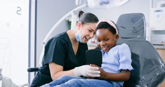 Dentist with a young girl patient smiling