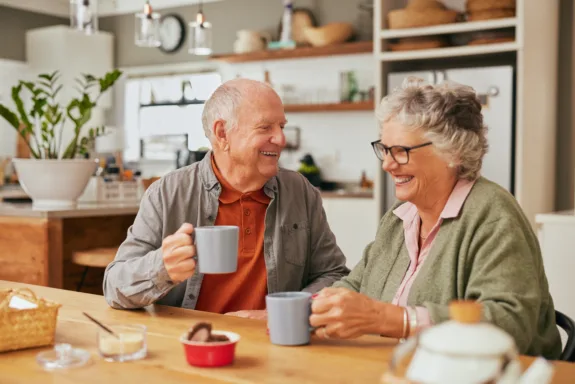 Smiling old couple sitting at table and sharing coffee